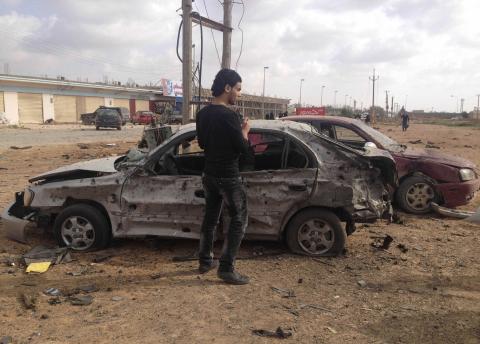 A man stands next to a car damaged after an explosion in the eastern city of Benghazi