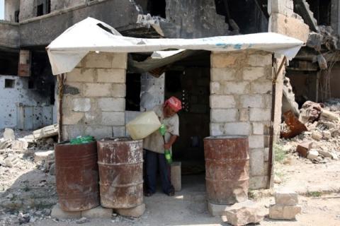 A man prepares fuel for sale near damaged buildings in the rebel-held area in Deraa, Syria July 27, 2017. PHOTO BY REUTERS/Alaa al-Faqir