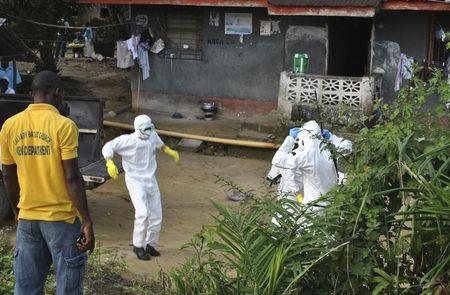 Medical staff wearing protective suits gather at a health facility near the Liberia-Sierra Leone border in western Liberia, November 5, 2014. PHOTO BY REUTERS/James Giahyue