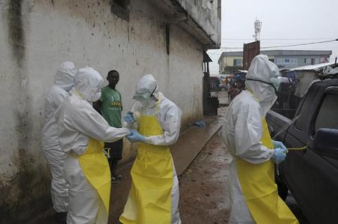 Health workers wearing protective clothing prepare before carrying an abandoned dead body presenting with Ebola symptoms at Duwala market in Monrovia, August 17 2014. PHOTO BY REUTERS/2Tango