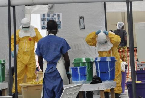 A Doctors Without Borders health worker takes off his protective gear under the surveillance of a colleague at a treatment facility for Ebola victims in Monrovia, September 29, 2014. PHOTO BY REUTERS/James Giahyue