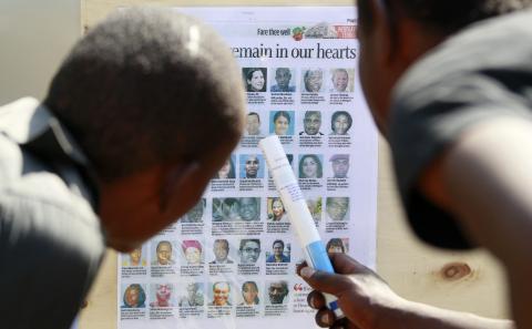 Men look at a newspaper cutting shows pictures of the slain victims who were killed in the recent Westgate shopping mall attack