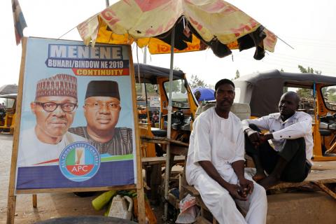 Men sit near a poster depicting Nigeria's President Muhammadu Buhari, after the postponement of the presidential election in Yola, Adamawa State, Nigeria, February 16, 2019. PHOTO BY REUTERS/Nyancho NwaNri