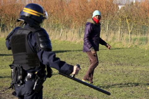 A French riot policeman stops migrants in a field near Calais, France, as migrants gather in the hopes of attempting to board lorries and making their way across the Channel to Britain, January 21, 2016. PHOTO BY REUTERS/Pascal Rossignol