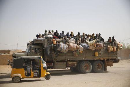 Migrants sit on their belongings in the back of a truck as it is driven through a dusty road in the desert town of Agadez, Niger, May 25, 2015. PHOTO BY REUTERS/Akintunde Akinleye