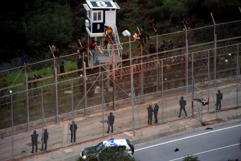 African migrants sit on top of a border fence during an attempt to cross into Spanish territories, between Morocco and Spain's north African enclave of Ceuta, December 9, 2016. PHOTO BY REUTERS/M. Martin