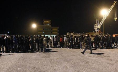 Police escort migrants as they are disembarked from a navy ship in the Sicilian harbour of Augusta, March 4, 2015. PHOTO BY REUTERS/Antonio Parrinello