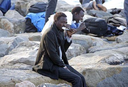 Migrants brush their teeth on the rocks of the seawall at the Saint Ludovic border crossing on the Mediterranean Sea between Vintimille, Italy and Menton, France, June 15, 2015. PHOTO BY REUTERS/Eric Gaillard