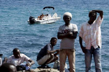 A man fishes from his boat as a group of migrants gather on the seawall at the Saint Ludovic border crossing on the Mediterranean Sea between Vintimille, Italy and Menton, France, June 14, 2015. PHOTO BY REUTERS/Eric Gaillard