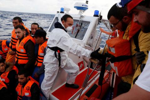 An Italian Coast Guard sailor helps a Libyan migrant on crutches to disembark from the migrant search and rescue vessel MV Seefuchs of the German NGO Sea-Eye, to be transferred to the Italian Coast Guard vessel Dattilo (not pictured) in international waters off the coast of Libya, October 2, 2017. PHOTO BY REUTERS/Darrin Zammit Lupi