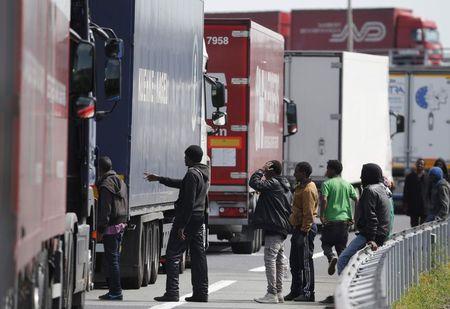 A group of migrants gather near a line of lorries waiting on the motorway which leads to the Channel Tunnel terminal in Calais, northern France, June 24, 2015. PHOTO BY REUTERS/Christian Hartmann