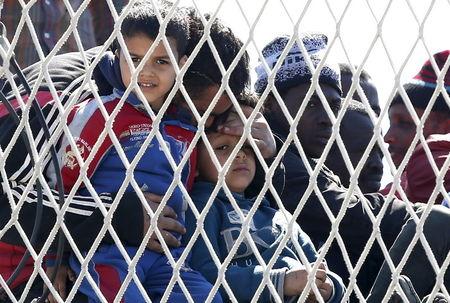 A man embraces his sons as they arrive with migrants at the Sicilian harbor of Augusta, April 22, 2015. PHOTO BY REUTERS/Alessandro Bianchi