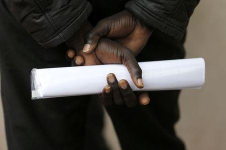 A migrant who seeks asylum holds documents as he gathers outside the Under Prefecture administration building in Calais, France, August 20, 2015. PHOTO BY REUTERS/Regis Duvignau