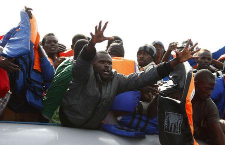 A group of 104 sub-Saharan Africans on board a rubber dinghy reach out for life jackets tossed to them by rescuers of the NGO Migrant Offshore Aid Station (MOAS) some 25 miles off the Libyan coast, October 4, 2014. PHOTO BY REUTERS/Darrin Zammit Lupi