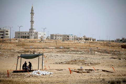 A mosque is seen in the background, as archaeology workers stand beneath a shade near the remains of a mosque (R), discovered by the Israel Antiquities Authority, which they say is one of the world's oldest, in the outskirts of the Bedouin town of Rahat in southern Israel, July 18, 2019. PHOTO BY REUTERS/Amir Cohen