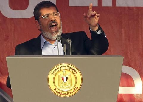 Egypt's Islamist President-elect Mohamed Mursi (R) delivers a speech while surrounded by his body guards in Cairo's Tahrir Square