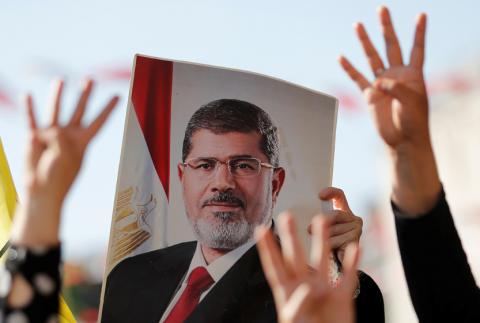 People flash Rabia signs as they hold a picture of former Egyptian president Mohamed Mursi during a symbolic funeral prayer at the courtyard of Fatih Mosque in Istanbul, Turkey, June 18, 2019. PHOTO BY REUTERS/Murad Sezer