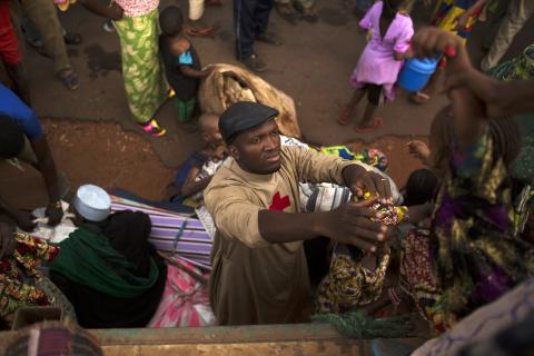 Father Bernard Kenvi (C) helps a Muslim child climb down from an open truck in the town of Bossemptele, west of Central African Republic