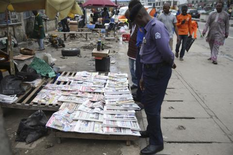 People read newspaper headlines at a vendor's stand along a road in Ikoyi district in Lagos