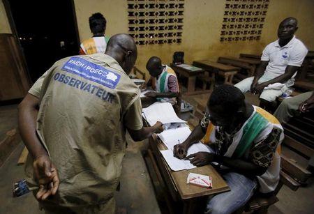 Election observer stands near polling workers as they count the ballots at a polling station in Yamoussoukro, Ivory Coast, October 25, 2015. PHOTO BY REUTERS/ Thierry Gouegnon