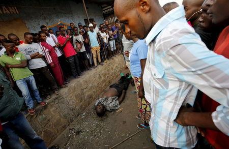 Onlookers gather around the body of man in the streets of Bujumbura's Niyakabiga district on presidential election day in Burundi, July 21, 2015. PHOTO BY REUTERS/Mike Hutchings