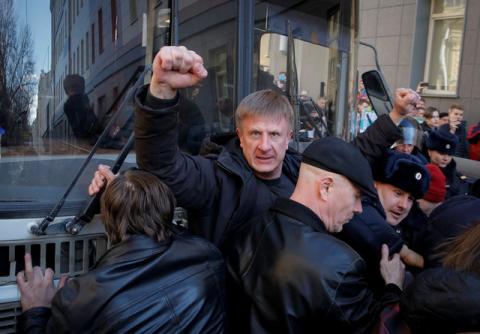 An opposition supporter gestures as he blocks a police van transporting detained anti-corruption campaigner and opposition figure Alexei Navalny during a rally in Moscow, Russia, March 26, 2017. PHOTO BY REUTERS/Maxim Shemetov