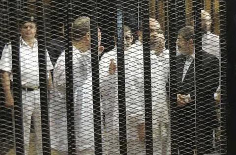 Ousted former Egyptian president Mohamed Mursi (R) speaks with other senior figures of the Muslim Brotherhood in a cage in a courthouse