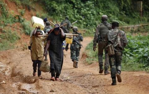 Democratic Republic of Congo (FARDC) military personnel walk past women as they patrol against the Allied Democratic Forces (ADF) and the National Army for the Liberation of Uganda (NALU) rebels near Beni in North-Kivu province, December 31, 2013. PHOTO BY REUTERS/Kenny Katombe