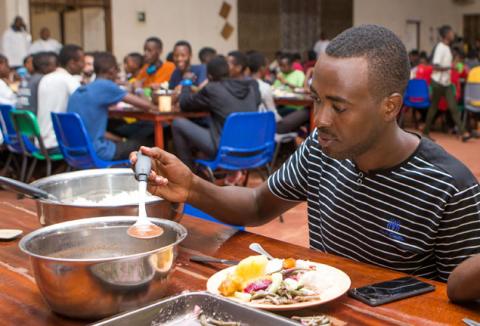 Ruhumuriza Vincent De Paul, who was orphaned by genocide, puts a meal on a plate in the dinning hall at the Agahozo-Shalom Youth Village (ASYV) built to rehabilitate children who lost their families in the 1994 Rwandan genocide, in Rwamagana, Eastern Province of Rwanda, April 1, 2019. PHOTO BY REUTERS/Jean Bizimana