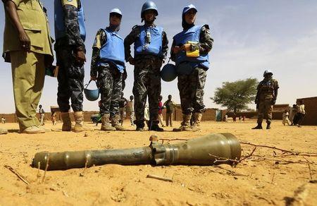 Peacekeepers from the United Nations Hybrid Operation in Darfur (UNAMID) look at an RPG-7 projectile that was found at the Al-Abassi camp for internally displaced persons, after an attack by rebels, in Mellit town, North Darfur, March 25, 2014. PHOTO BY REUTERS/Mohamed Nureldin Abdallah