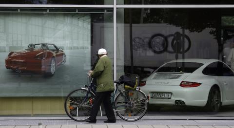 A unidentified pedestrian walks past a shopping window of a Porsche car dealer in Munich June 22, 2009. Facing an expected rejection from Berlin for its state loan request and in need of a capital infusion, heavily indebted Porsche SE could be running out of options to repair its sagging balance sheet. PHOTO BY REUTERS/Michael Dalder