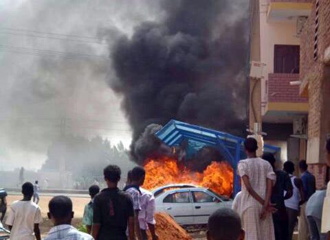 People look at burning cars during protests over fuel subsidy cuts in Khartoum