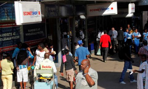 A Zimbabwean man speaks on his phone outside a branch of mobile service provider Econet Wireless in central Harare, June 6, 2014. PHOTO BY REUTERS/Philimon Bulawayo