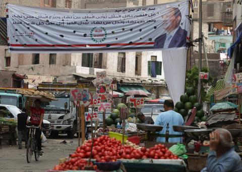 People walk in a market near an electoral banner for presidential candidate and former army chief Abdel Fattah al-Sisi during the third day of voting in the Egyptian presidential election in Cairo