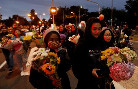 People reacts as they move the flowers after police removed a police line, outside Masjid Al Noor in Christchurch, New Zealand, March 16, 2019. PHOTO BY REUTERS/Jorge Silva