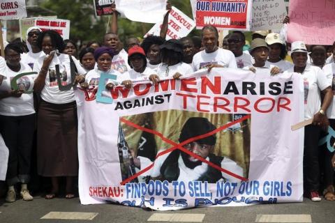 People carry a banner with an image of Boko Haram leader?Abubakar?Shekau?as they protest for the release of the abducted secondary school girls in the remote village of Chibok, along a road in Lagos