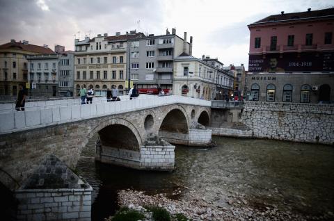 People cross the Latin Bridge and street corner in front of the historical landmark, where Archduke Franz Ferdinand and his wife Sophie were assassinated, in Sarajevo