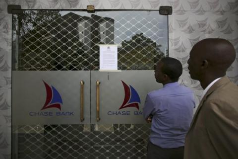 People read a notice from the Central Bank of Kenya taped to the closed entrance of a Chase Bank branch, after the bank was put under receivership, in Nairobi, Kenya, April 8, 2016. PHOTO BY REUTERS/Siegfried Modola