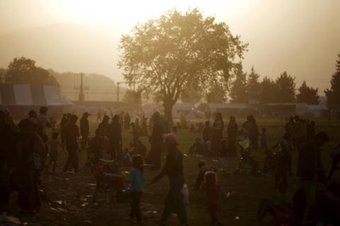 People gather in a field as the sun sets at a makeshift camp for refugees and migrants at the Greek-Macedonian border near the village of Idomeni, Greece, April 14, 2016. PHOTO BY REUTERS/Stoyan Nenov