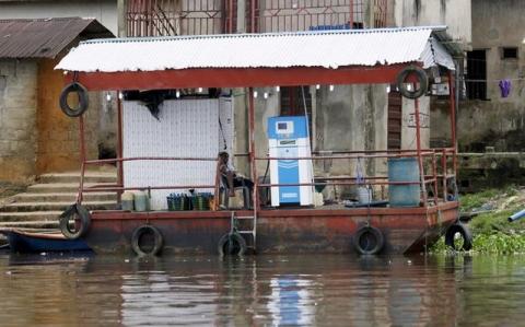 A petrol attendant sits on a floating fuel station on the banks of the Nun River on the outskirts of the Bayelsa state capital, Yenagoa, in Nigeria's delta region, October 8, 2015. PHOTO BY REUTERS/Akintunde Akinleye