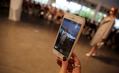 A spectator uses her mobile to record Animale's Winter 2016 collection, during Sao Paulo Fashion Week, October 19, 2015. PHOTO BY REUTERS/Nacho Doce