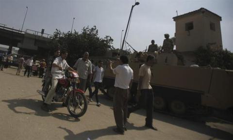 Plainclothes police officers conduct a check on a motorcycle in front of Boulaq Al-Dakrour police station