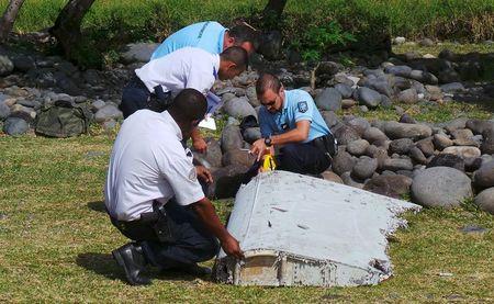 French gendarmes and police inspect a large piece of plane debris which was found on the beach in Saint-Andre, on the French Indian Ocean island of La Reunion, July 29, 2015. PHOTO BY REUTERS/Prisca Bigot