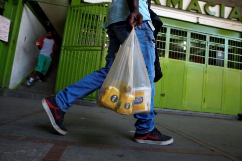 Man carries a plastic bag of basic foods after buying them during a special inspection by Venezuelan soldiers to a municipal market in Caracas, Venezuela, July 15, 2016. PHOTO BY REUTERS/Carlos Garcia Rawlins