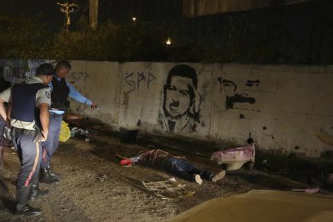 Police officers stand near the body of Anzoategui state policeman Mario Figueroa after he was shot dead in Barcelona, in the state of Anzoategui, January 24, 2015. PHOTO BY REUTERS/Stringer