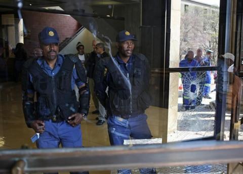 Police officers are reflected in a damaged window after students clashed with security at University of the Witwatersrand as countrywide protests demanding free tertiary education entered a third week, Johannesburg, South Africa, September 20, 2016. PHOTO BY REUTERS/Siphiwe Sibeko