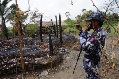 A Myanmar border guard police officer takes pictures at the remains of a burned house in Tin May village, northern Rakhine state, Myanmar, July 13, 2017. PHOTO BY REUTERS/Simon Lewis