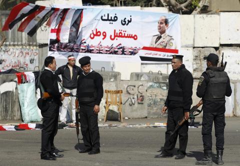 Police officers stand guard in front of banners supporting Egypt's army chief General Abdel Fatah al-Sisi during celebrations of the third anniversary of Egypt's uprising at El-Thadiya presidential palace in Cairo