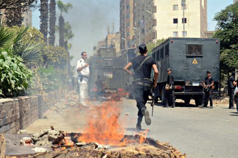 Police take positions after a protest was dispersed quickly, leaving fire burning in a main street in Giza, south of Cairo