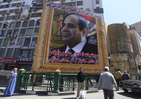 People stand under a huge banner of Egypt's former army chief Abdel Fattah al-Sisi in downtown Cairo